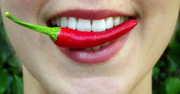 smiling girl with teeth holding a chili