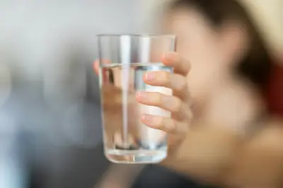 holding a clear glass of water 